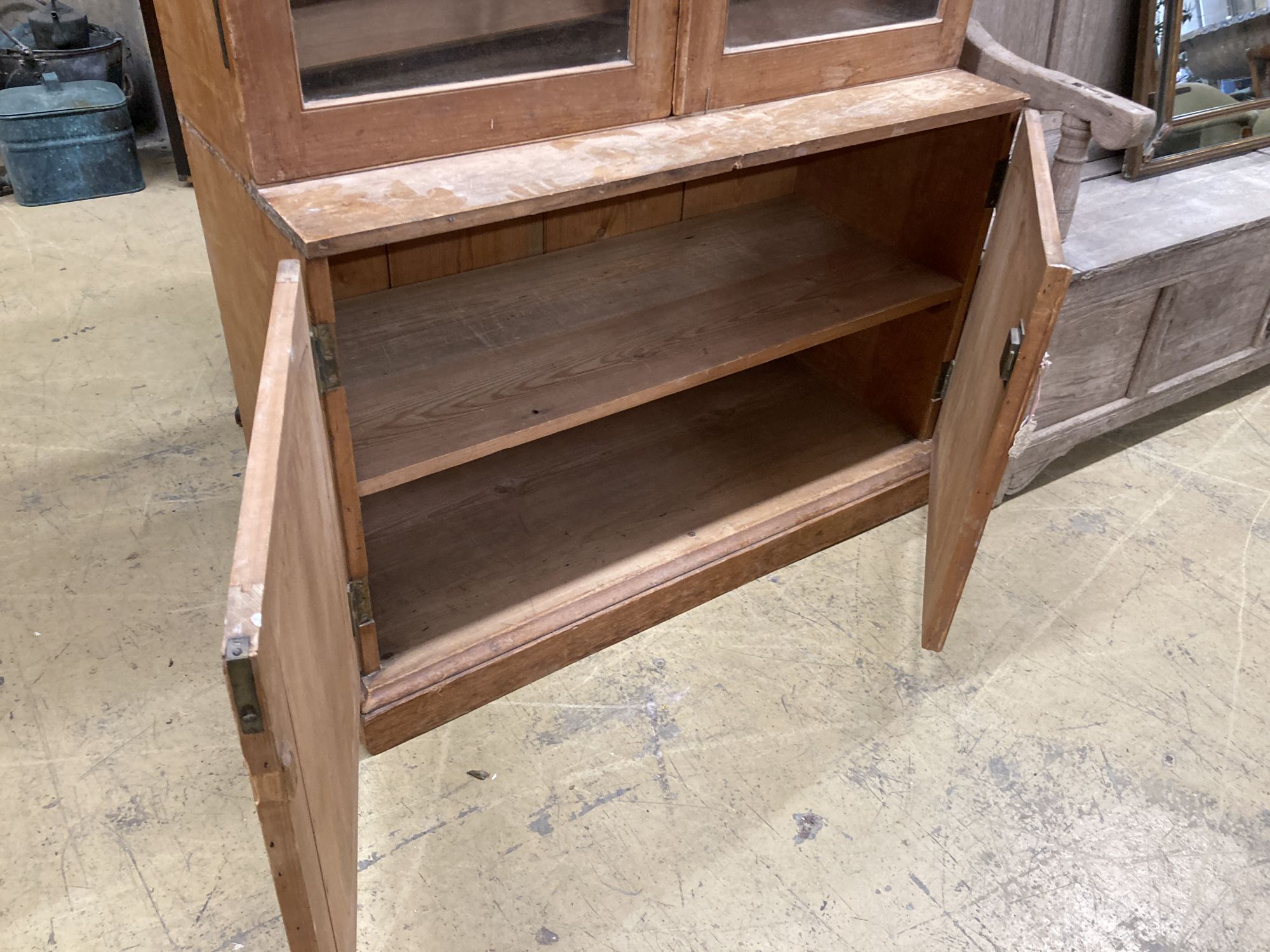 A glazed pine bookcase / cupboard, width 106cm, depth 46cm, height 196cm